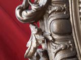 a large ornate silver mirror on a red background
