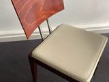 a wooden chair with a leather seat in front of a window