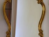 a gold mirror hanging on the wall next to a mirror