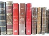 several old books are lined up on a shelf in a row