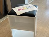 un tabouret noir et blanc sur lequel est posée une pancarte