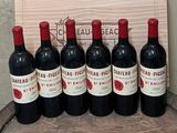 six bouteilles de vin rouge sont alignées sur un tonneau