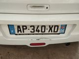 the rear end of a white car with a number plate on it