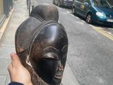 a person holding a mask on the sidewalk of a city street