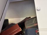 many suitcases and bags sitting in a small cabinet