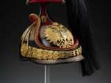 a red and gold helmet with a long black hair on a stand