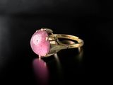 a close up of a pink stone ring on a black surface