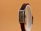 une montre posée sur un socle, sur une surface marron