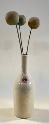 a white vase with three flowers in it on a table