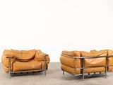 two brown leather sofas sitting next to each other on a cement floor