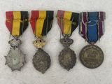 four medals are displayed on a white surface in a row
