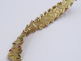 a close up of a gold bracelet on a white surface