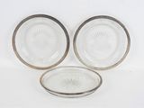 trois assiettes en verre à bordure argentée sont posées sur une surface blanche