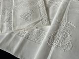 plusieurs serviettes blanches brodées, ornées de monogrammes, posées sur une table