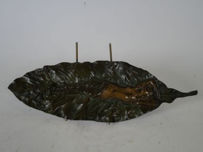 un bougeoir en forme de feuille sur lequel est posée une bougie