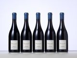 four bottles of red wine are lined up on a table