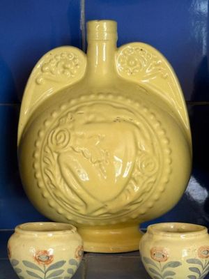un vase jaune et deux tasses posés sur une étagère