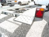 vehicles parked in a parking lot with a flatbed trailer attached to the back of it