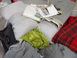 un tas de vêtements et un sac posés sur un lit