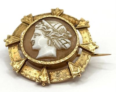 une image représentant une broche dorée et blanche avec une tête de femme au centre