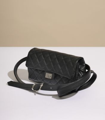 le sac matelassé noir est posé sur une table blanche