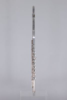 a silver flute on a clear stand against a gray background