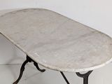 a marble top table with iron legs on a white floor