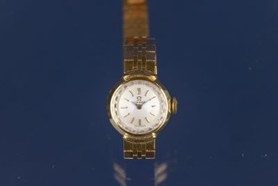 une montre en or posée sur une surface bleue