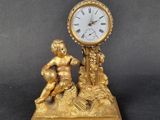 a gold clock sitting on top of a table next to a figurine