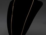 un collier à chaîne en or posé sur un présentoir noir pour mannequin