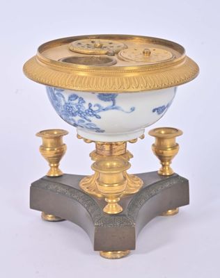 une horloge dorée et bleue posée sur un socle, sur fond blanc
