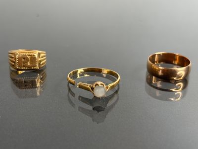 trois bagues en or et une bague ornée d'une perle, posées sur une table