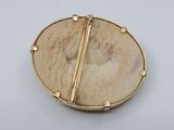 a close up of a gold plated broochle with a circular design