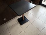 a black table with a wooden base on a tile floor