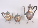 trois théières en argent et une théière posées sur une table