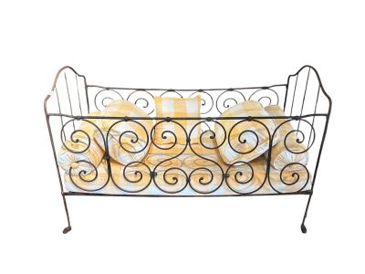 un lit en fer noir recouvert d'une couverture jaune et blanche
