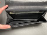 someone is holding a black purse with a zipper on the inside of it