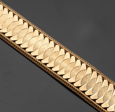 gros plan d'un bracelet en or sur une surface noire