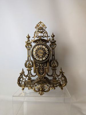 a gold clock sitting on top of a clear shelf