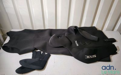 a black wet suit and a pair of flip flops on the floor