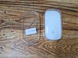 a white apple mouse and a clear case on a wooden table