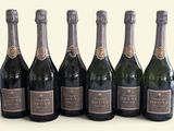 six bouteilles de champagne alignées sur une surface blanche