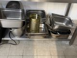several pans and pans are lined up on a shelf in a kitchen