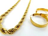 un collier en or et une bague en or posés sur une surface blanche