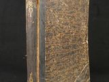 an old book sitting on top of a black table next to a black background