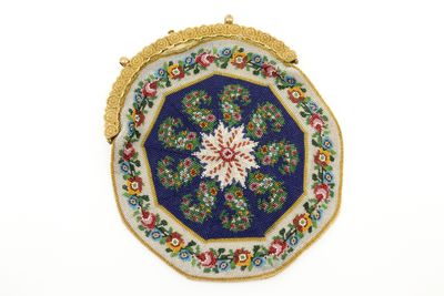 une image représentant un sac à main bleu et or orné d'un motif floral