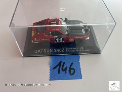 une voiture rouge dans une vitrine transparente, ornée d'un ruban bleu