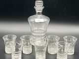 a lot of shot glasses and a decanter on the table