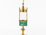 a gold and green candle holder with a cross on top of it