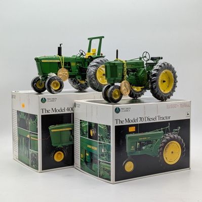 three toy tractors sitting on top of boxes on a table